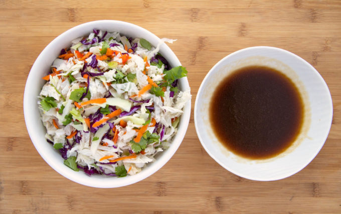 mixed ingredients for asian slaw and asian dressing in white bowls