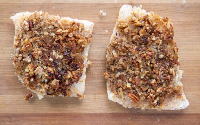 sauteed snapper fillets in a baking dish with the pecan side up