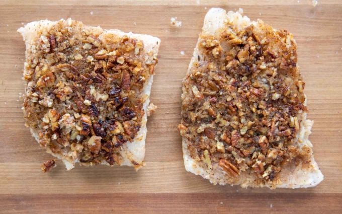 sauteed snapper fillets in a baking dish with the pecan side up