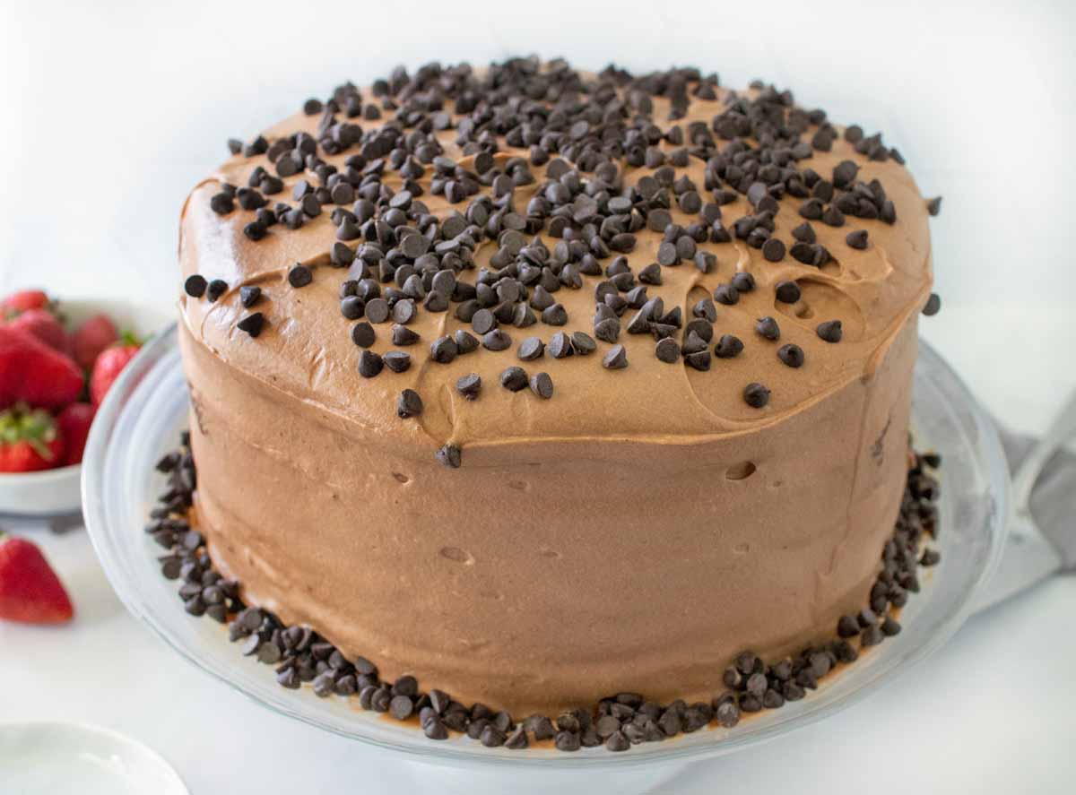 whole chocolate cake frosted and topped with chocolate chips on a platter