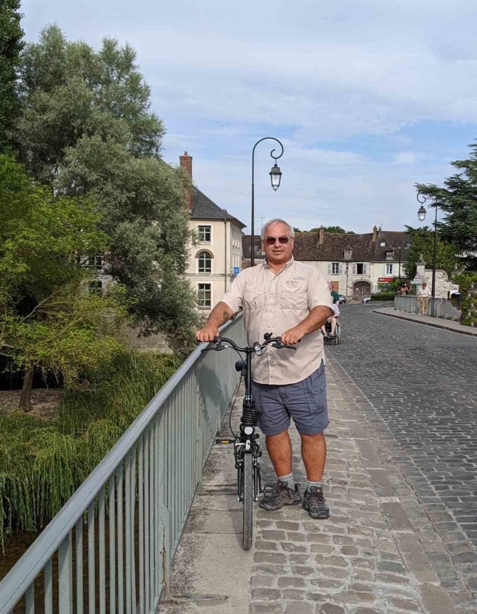 Chef Dennis holding a bike on a walkway in Moret sur Loing 