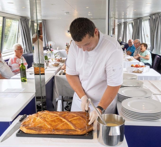 Chef cutting coulibiac of salmon onboard a cruise ship