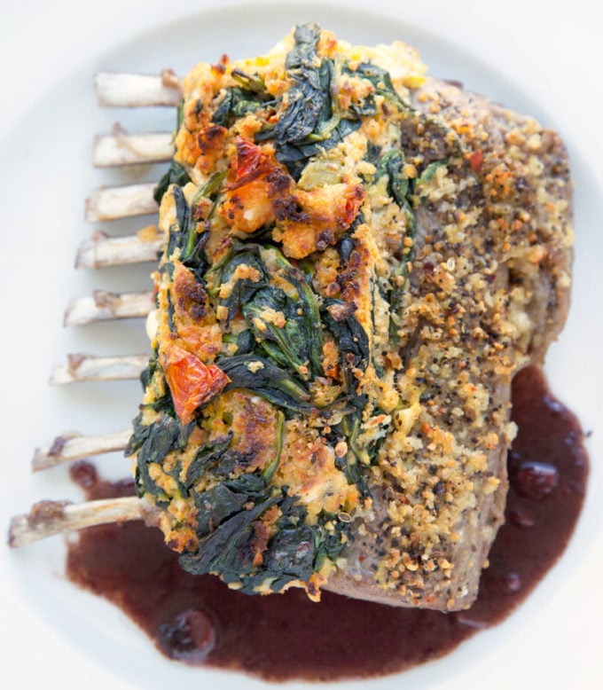 overhead view of stuffed and roasted rack of lamb  with sauce on a white plate