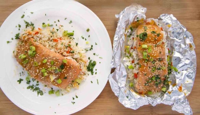 mango bourbon salmon on a white plate next to the mango salon on foil