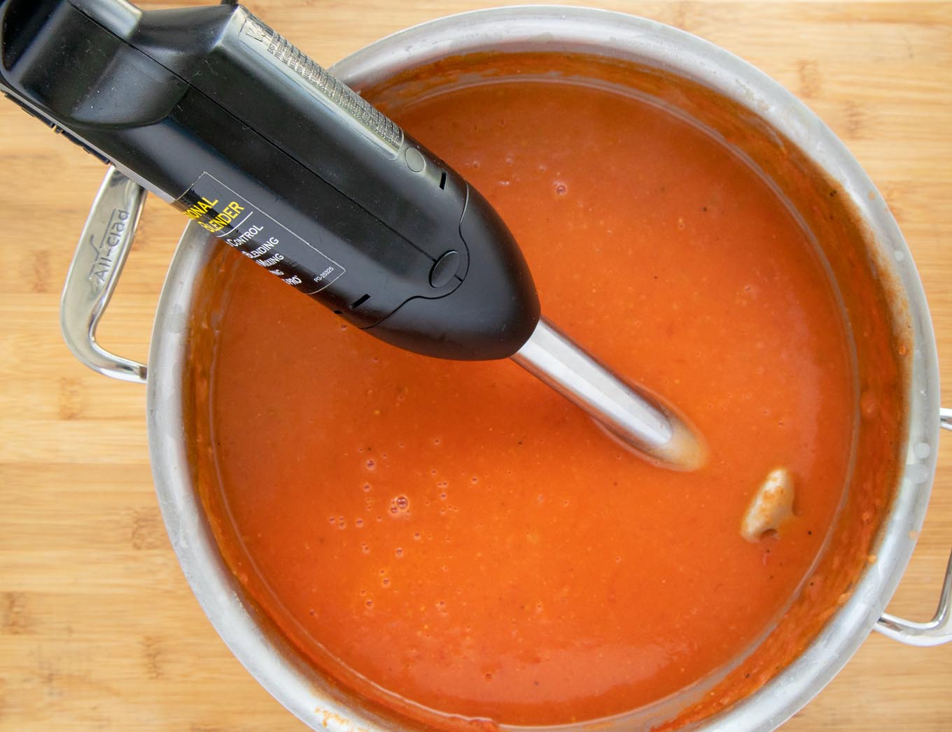 Tomato soup with immersion blender sticking out of the pot