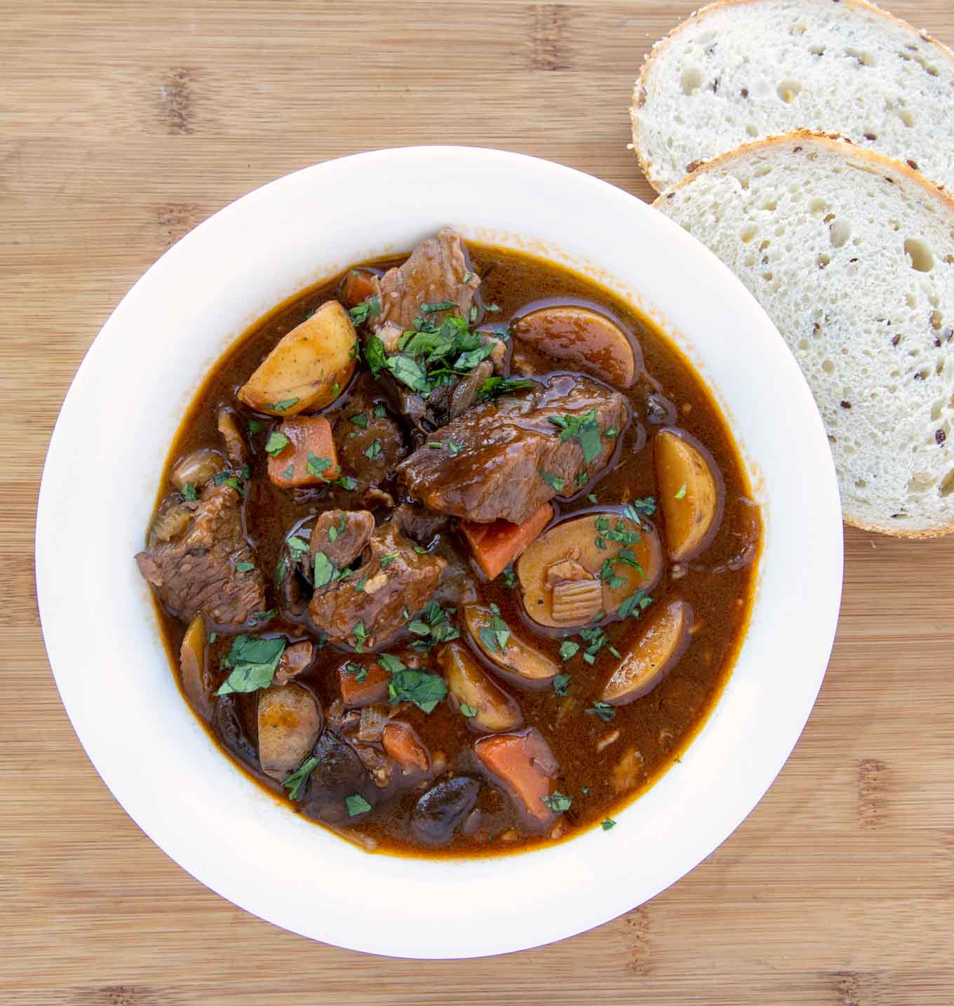 white bowl with Guinness beef stew and 2 slices of bread next to the bowl