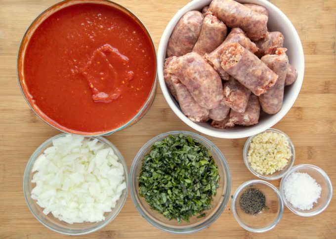 ingredients to make spaghetti sauce in bowls on a wooden cutting board