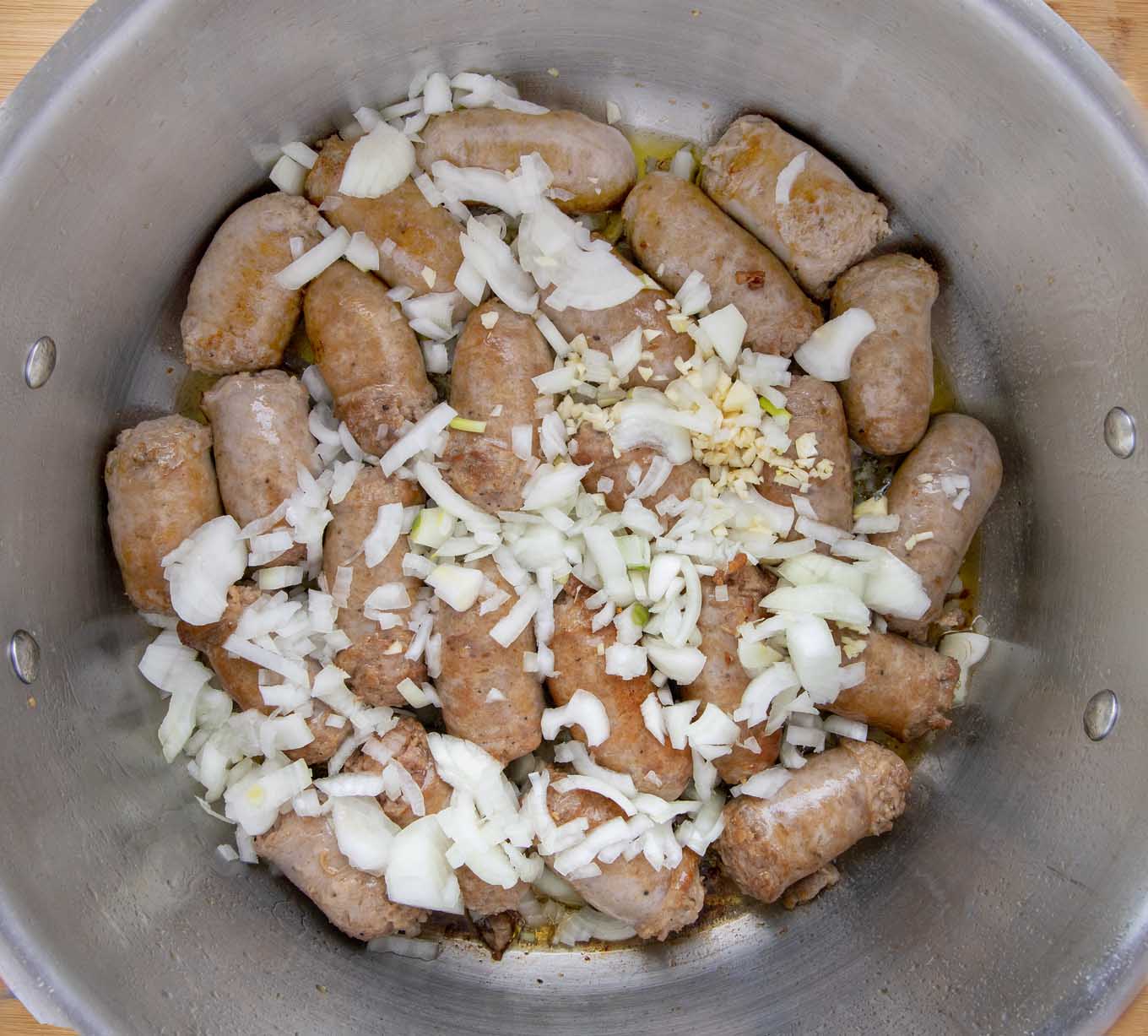 large pot with browned sausage and diced onion and garlic.