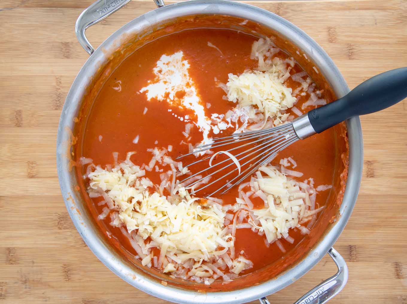 shredded cheddar and cream added to a big pot of tomato bisque
