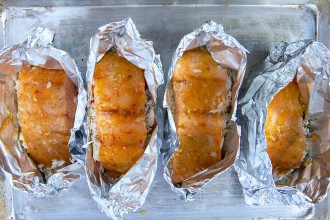 4 open foil packets of cooked mango bourbon salmon