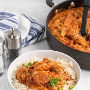 chicken gumbo over rice in a white bowl with a pot of chicken gumbo in the background