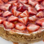 whole cheesecake topped with strawberries and glaze on a white plate