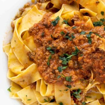 bolognese sauce served over pappardelle in a white bowl