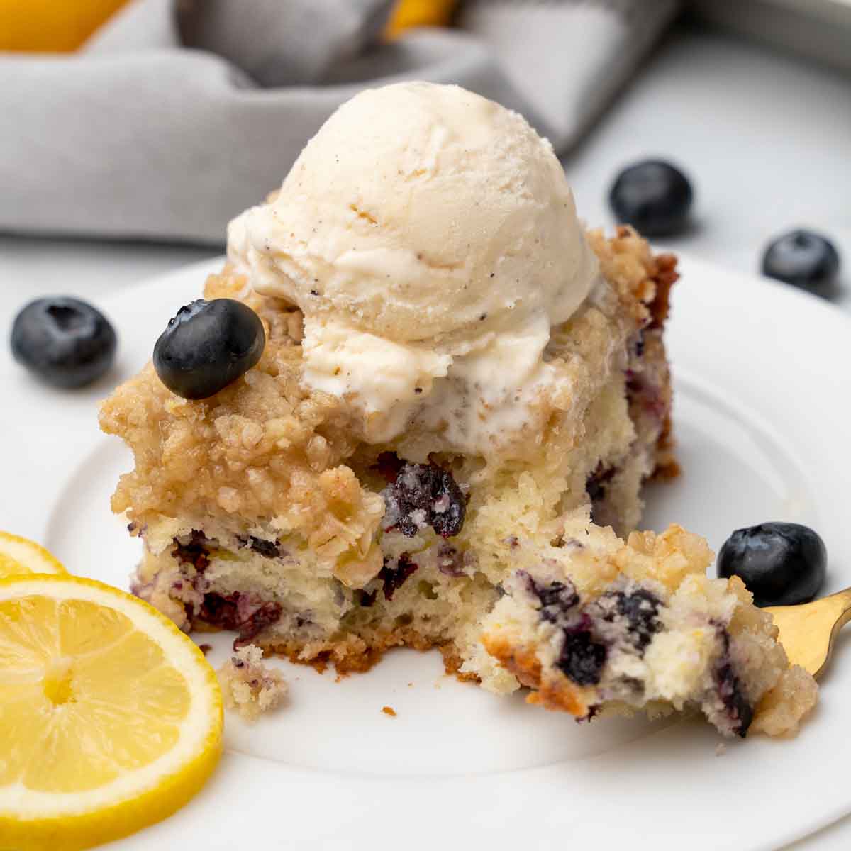 slice of blueberry buckle with a scoop of vanilla ice cream on top