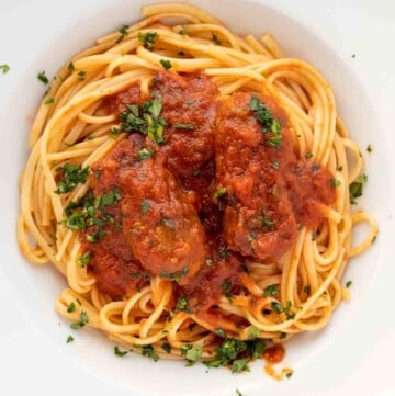 overhead shot of spaghetti with sausage in a white bowl