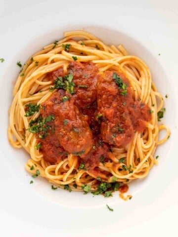 overhead shot of spaghetti with sausage in a white bowl