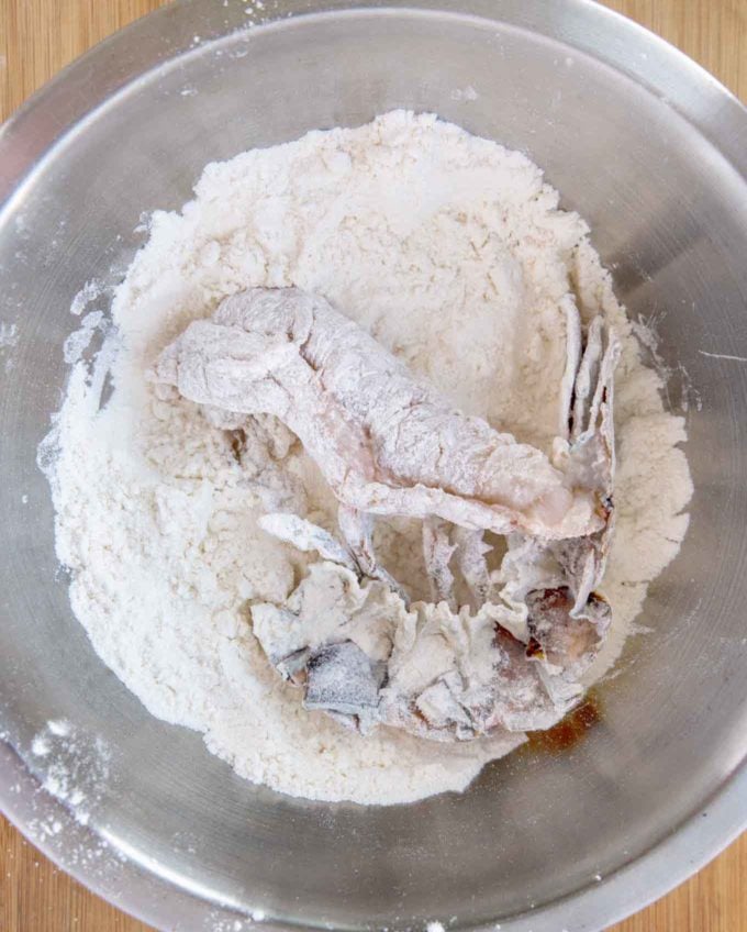 lobster tails in flour in a stainless steel bowl