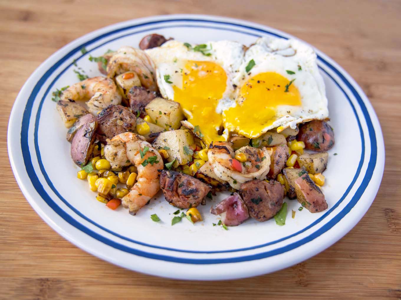 shrimp and andouille mixture with two sunny side up eggs with the yolks running on the misture