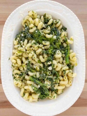 overhead shot of pasta aioli with broccoli rabe in a white oval bowl