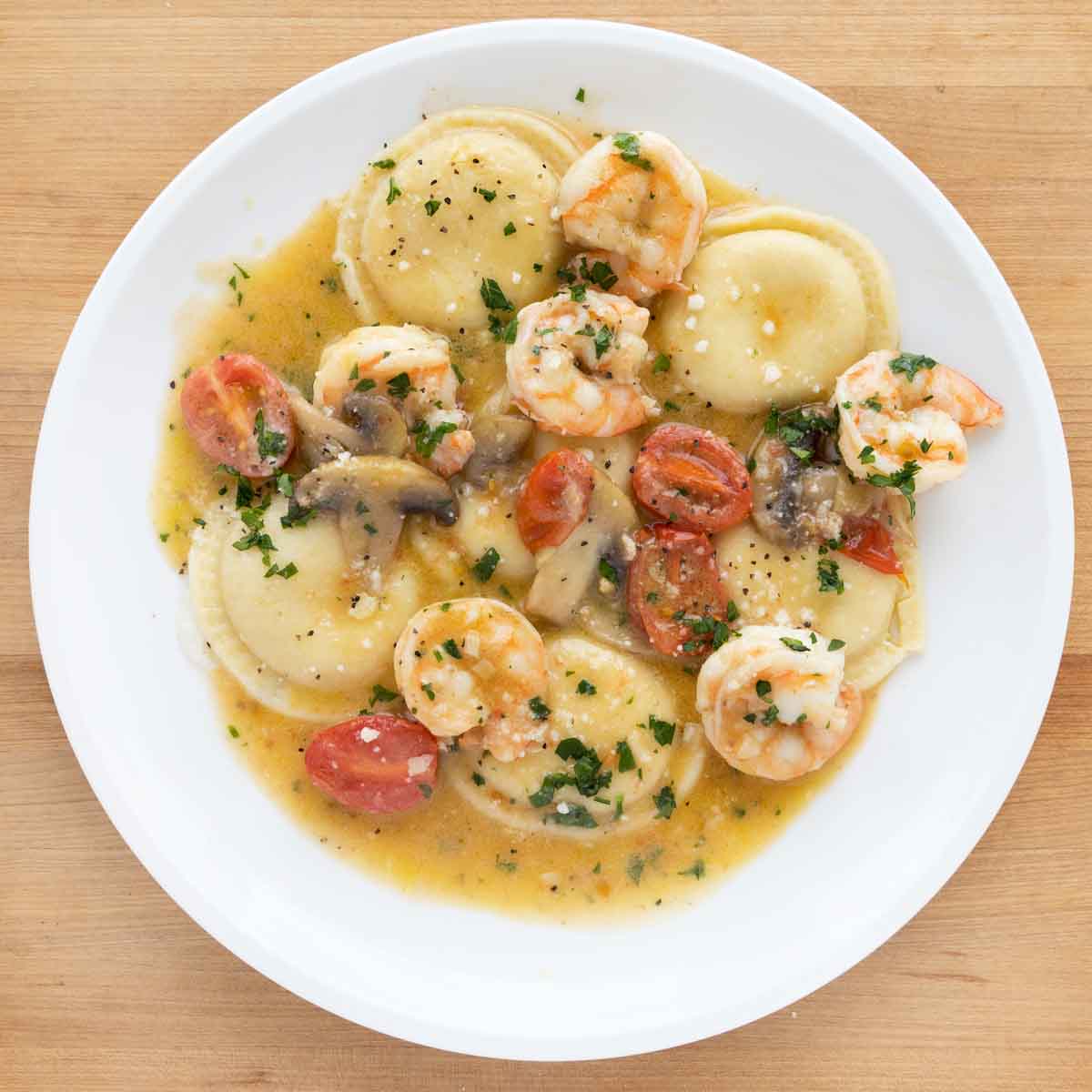 overhead shot of ravioli and shrimp scampi on a white plate