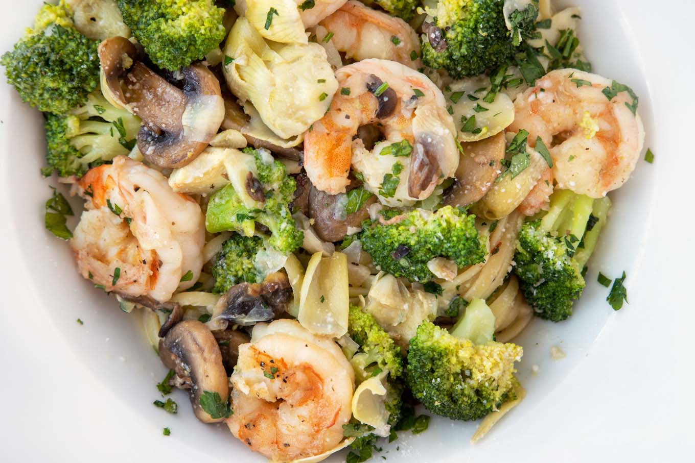 Shrimp and broccoli over linguine in a white bowl