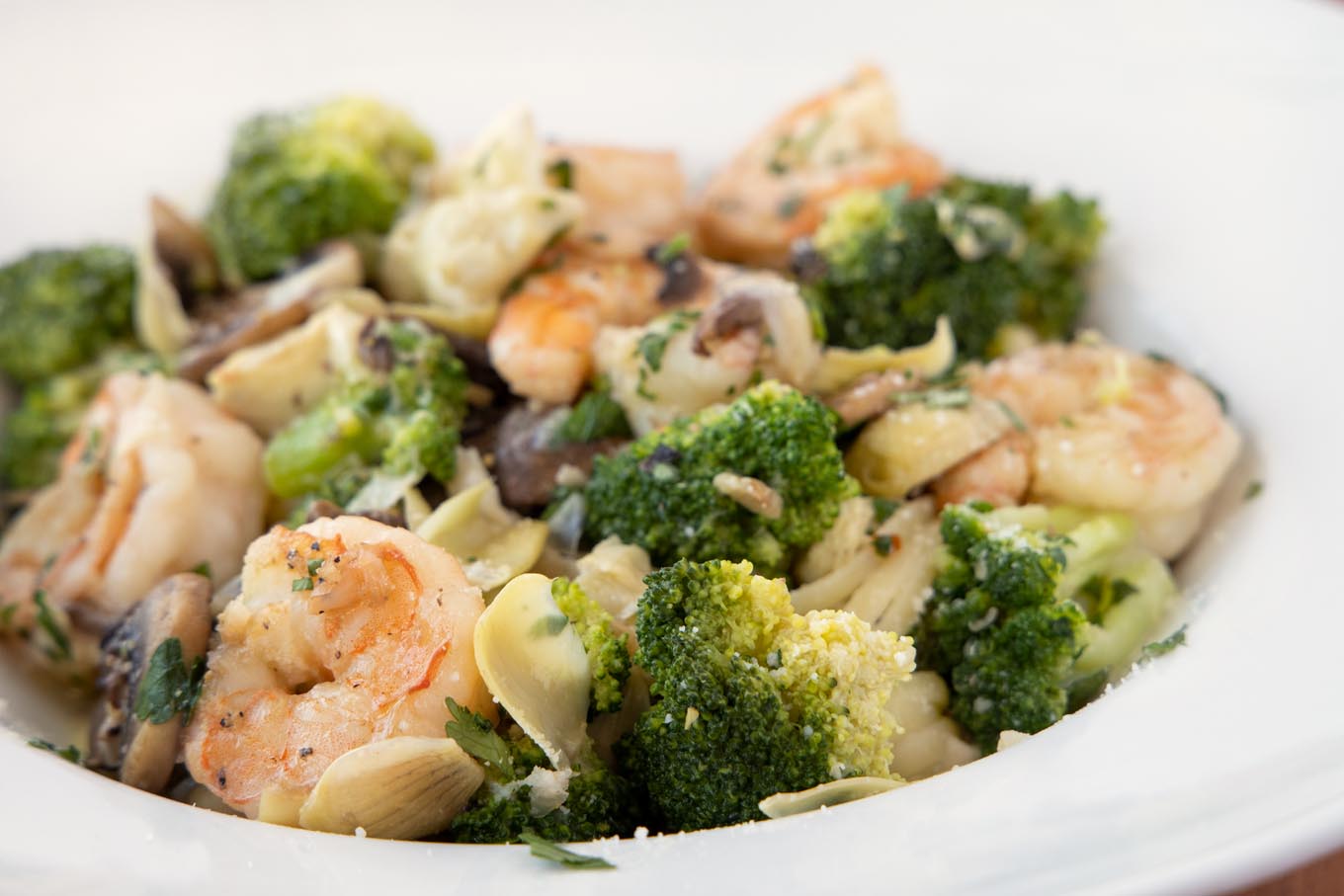 side view of shrimp and broccoli in a white bowl