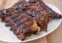 3 half racks of grilled baby back ribs on a white platter