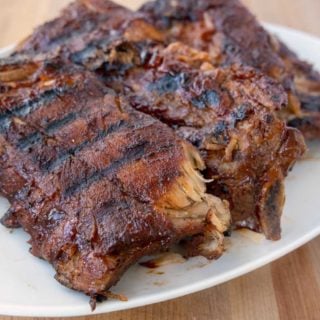 3 half racks of grilled baby back ribs on a white platter