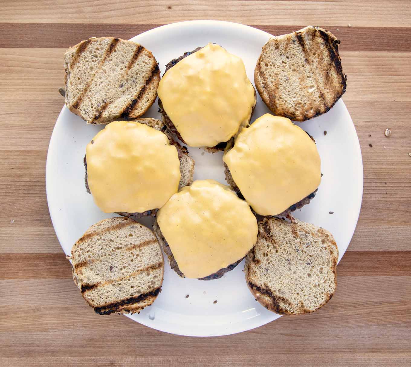 burgers with melted cheese and toasted buns on a white platter