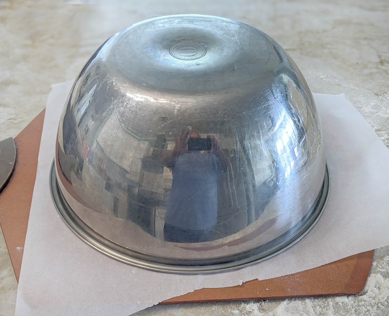 stainless steel bowl covering the bread dough on the pizza peel
