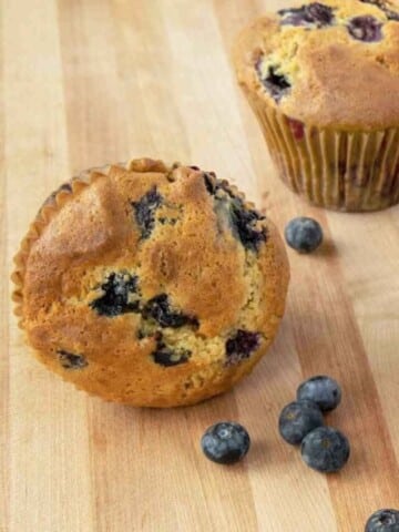 blueberry muffins with blueberries on a wooden cutting board