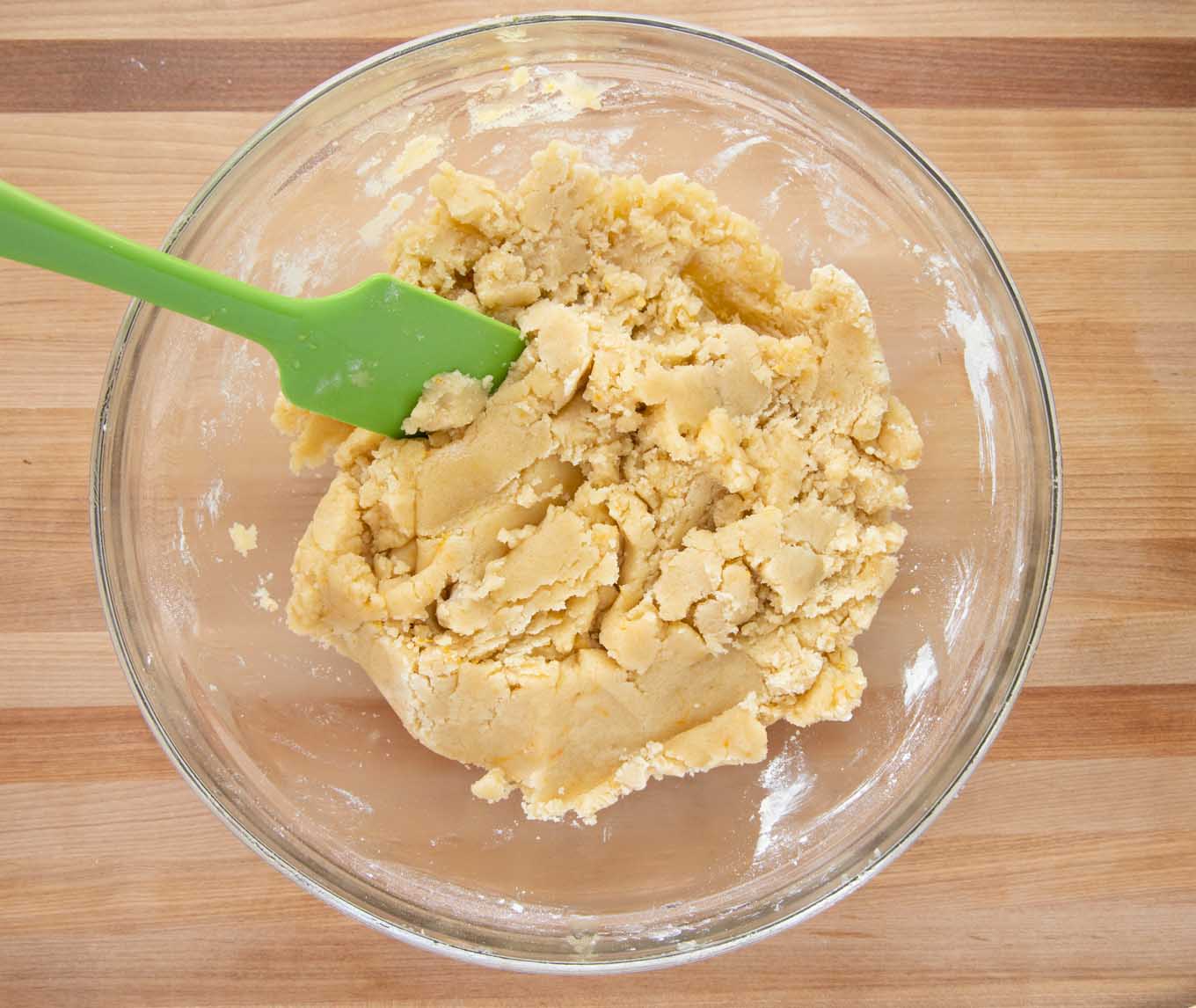 overhead view of the dough mixture in a glass bowl with a green spatula  without eggs 