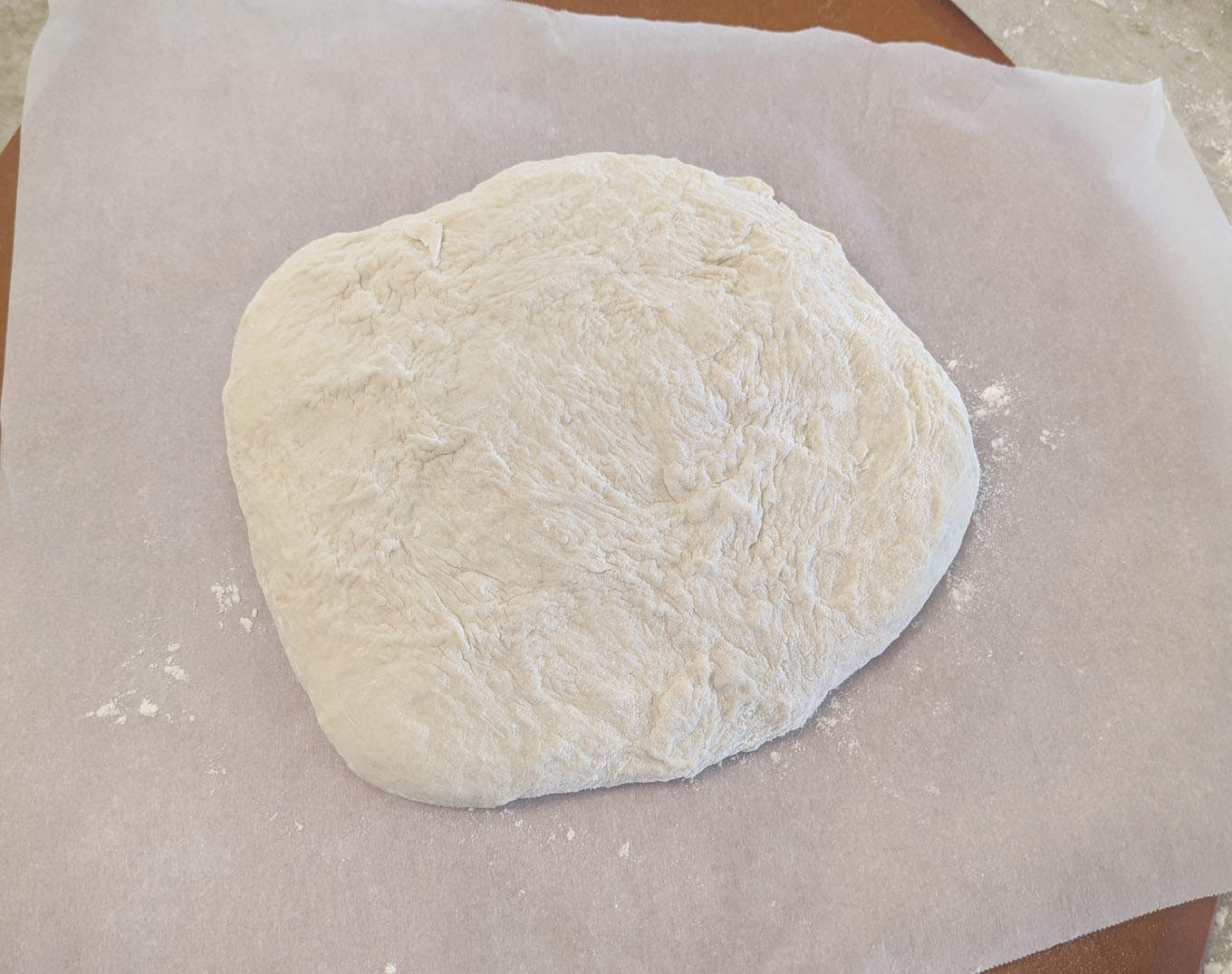 dough on parchment paper on pizza peel for the second rise