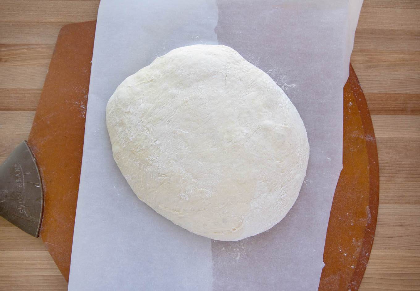 bread dough after the second rise on parchment paper on a pizza peel