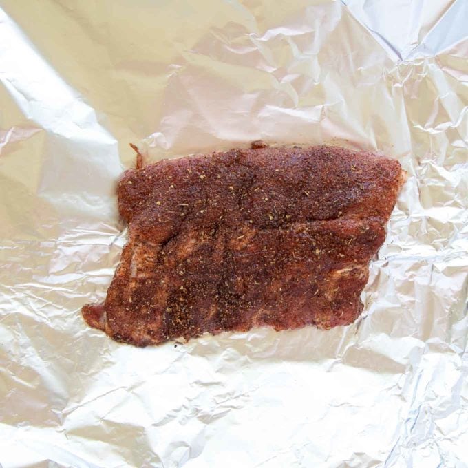 half rack of dry rubbed baby back ribs on sheet of foil