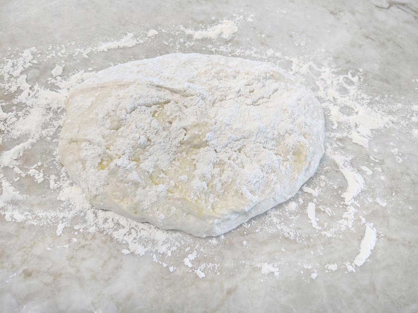 bread dough floured on a marble counter top