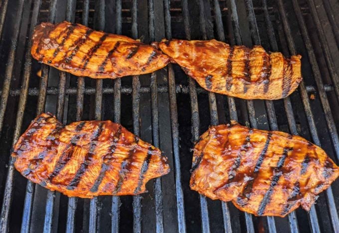 chicken breasts cooking on grill with grill marks on chicken