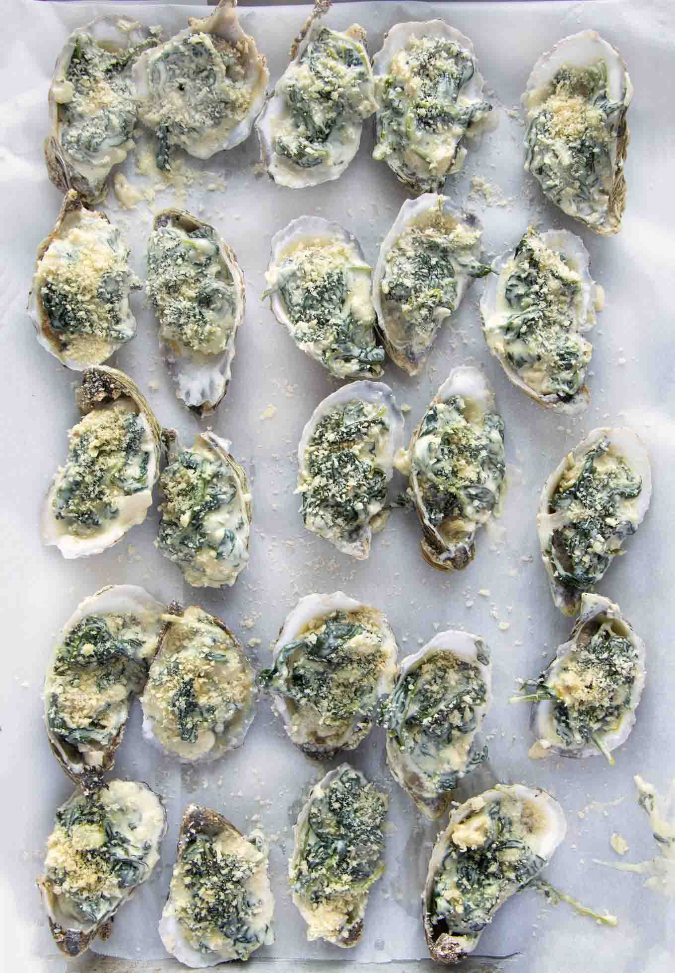 oysters topped with Rockefeller topping on a sheet pan
