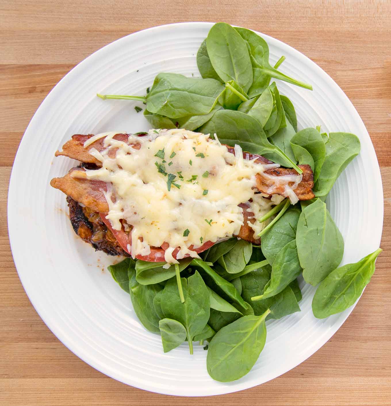 finished grilled chicken on bed of spinach on a white plate