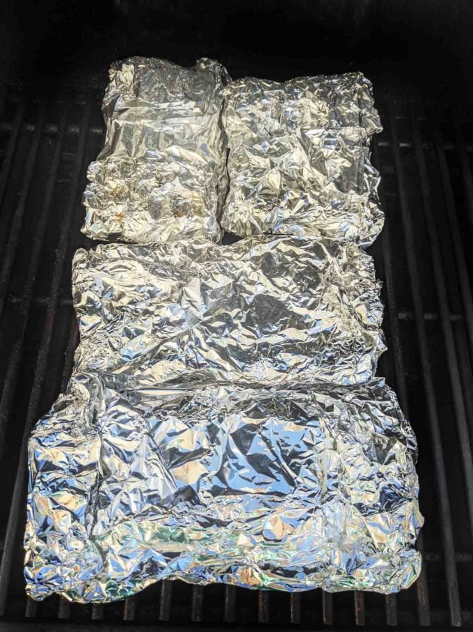 four packets of foil wrapped ribs on the grill