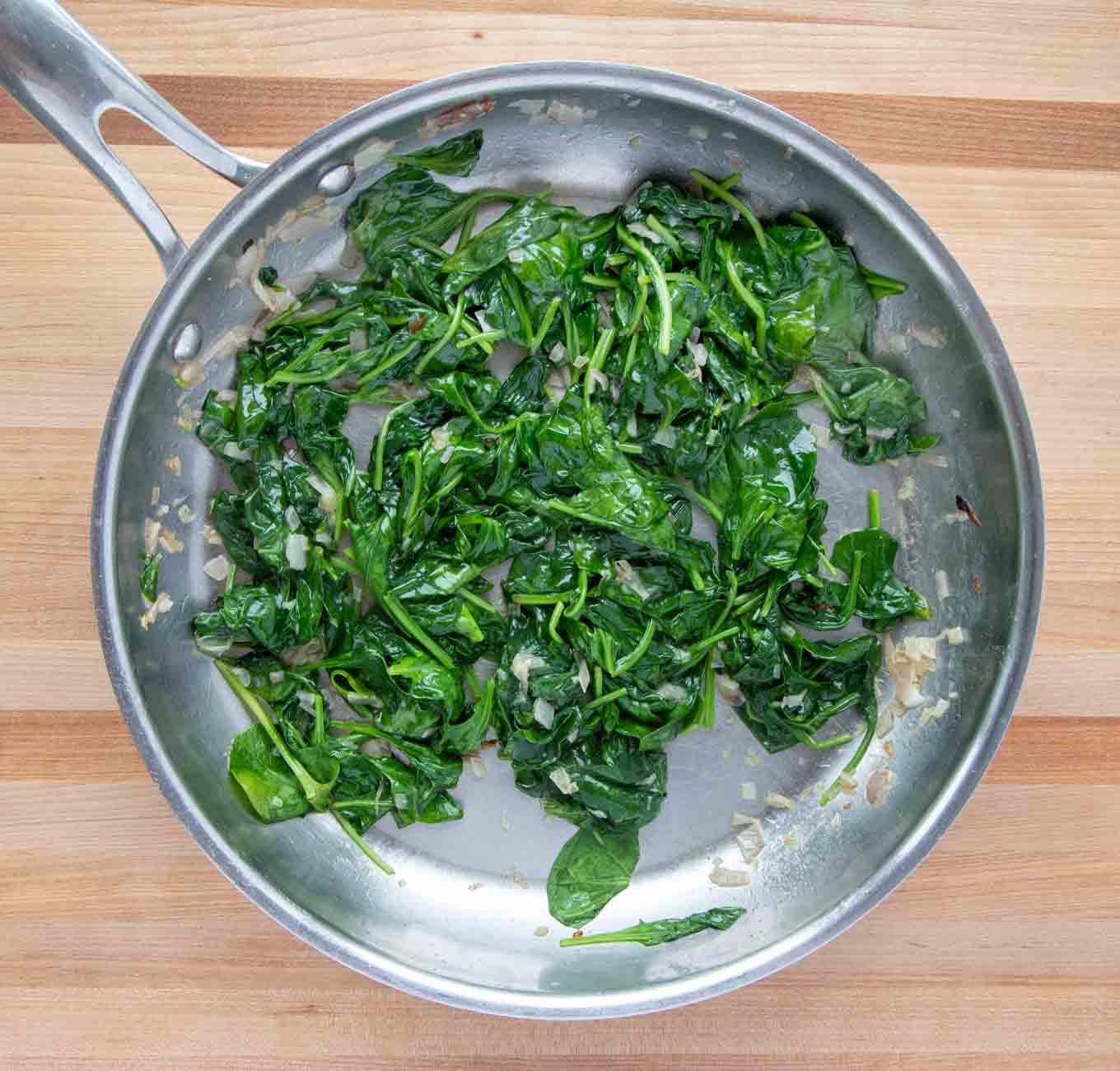 wilted spinach in a large saute pan