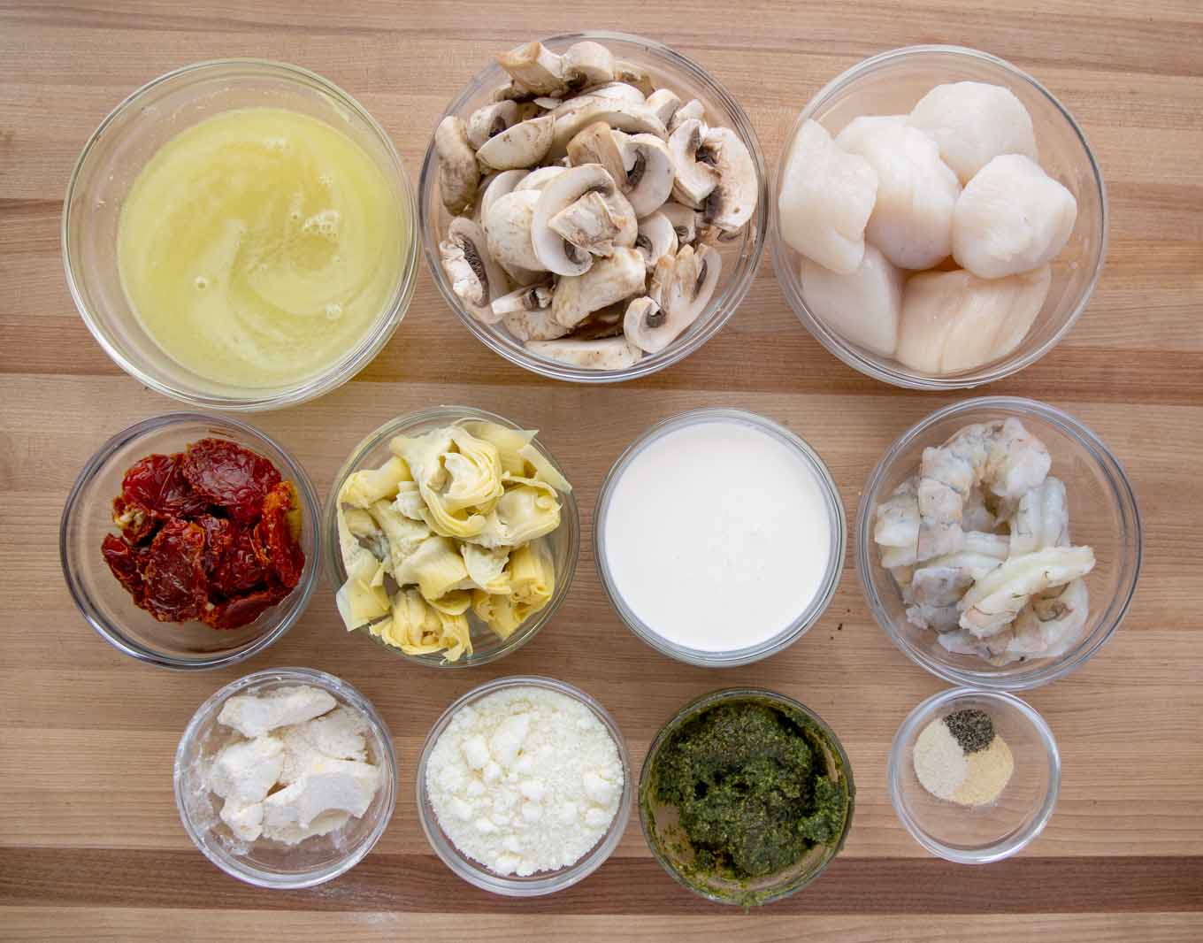 ingredients to make seafood riviera in glass bowls on a wooden cutting board