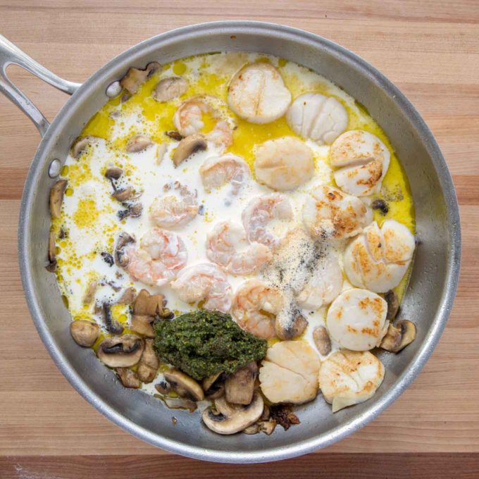saute pan with shrimp, scallops and mushrooms, with heavy cream, stock, pesto and seasonings added