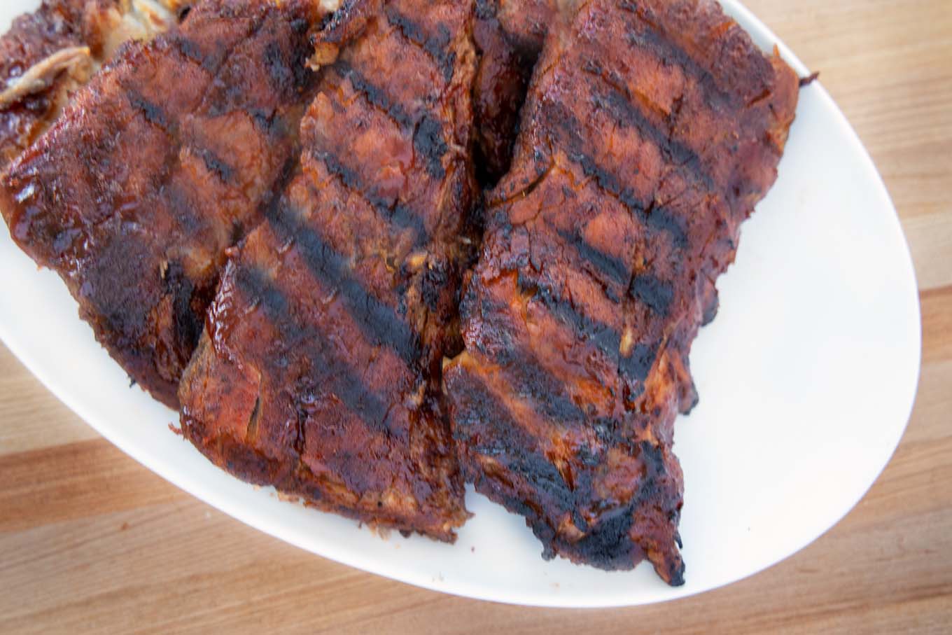 grilled baby back ribs on a white oval platter