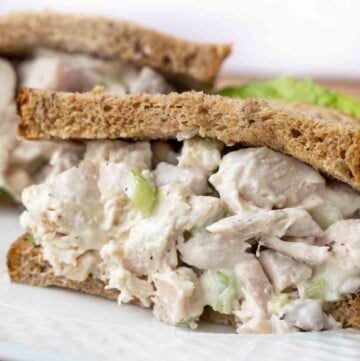 close up of half a chicken salad sandwich on a white plate