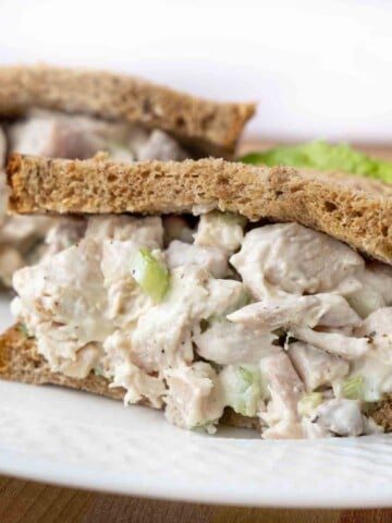 close up of half a chicken salad sandwich on a white plate