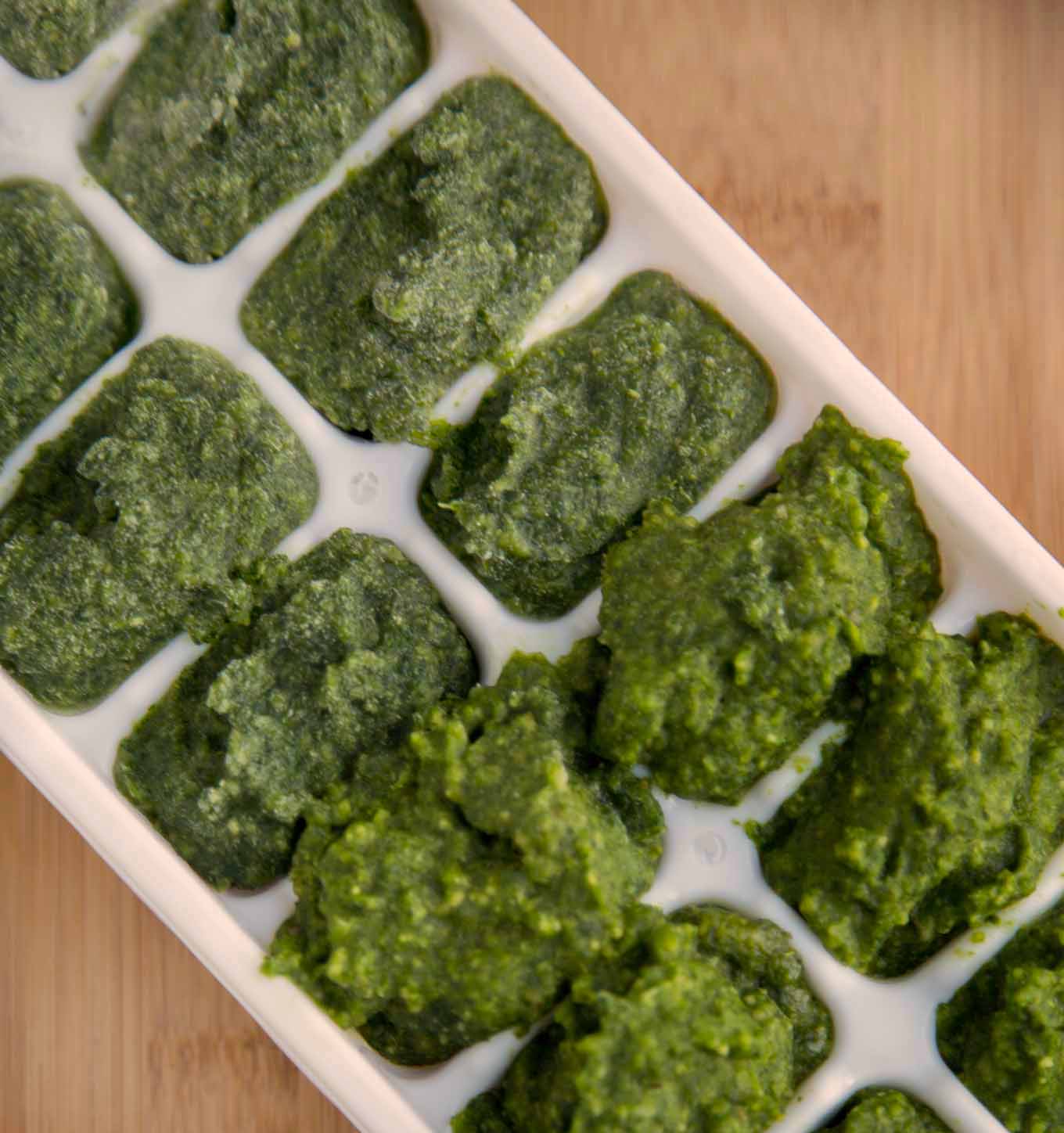 partial overhead shot of a white ice cube tray filled with pesto
