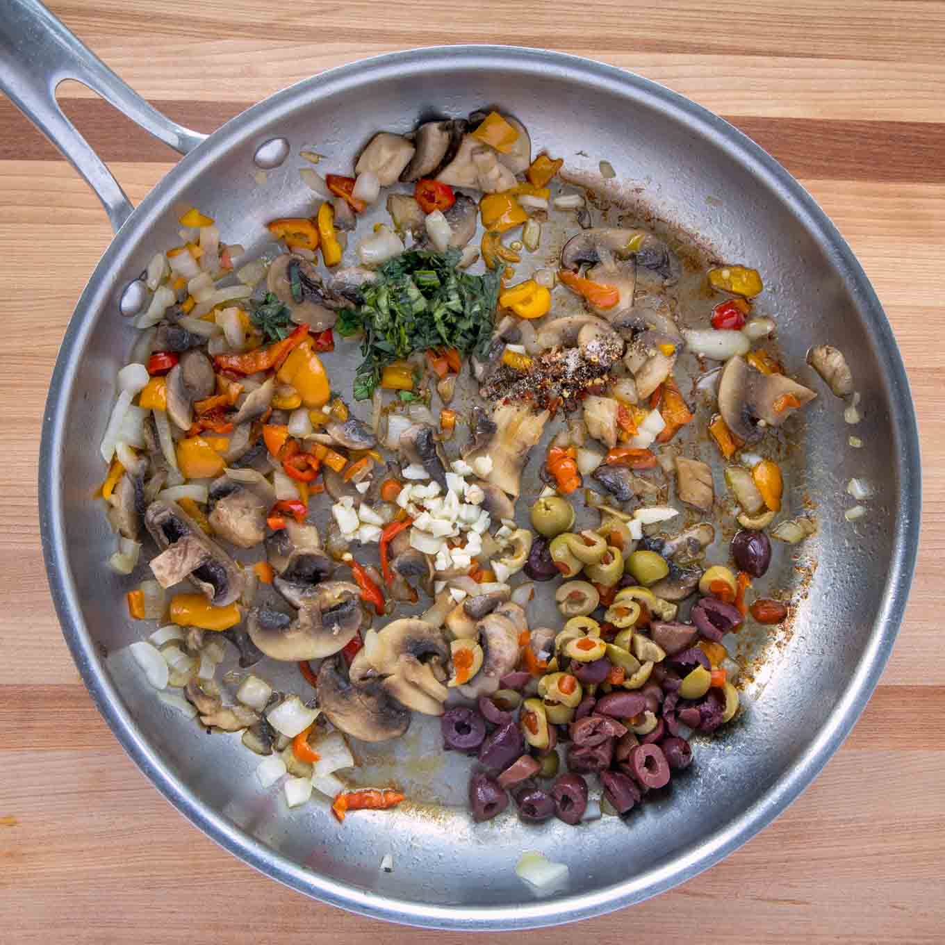 garlic, olives, basil and spices added to the sauteed vegetables