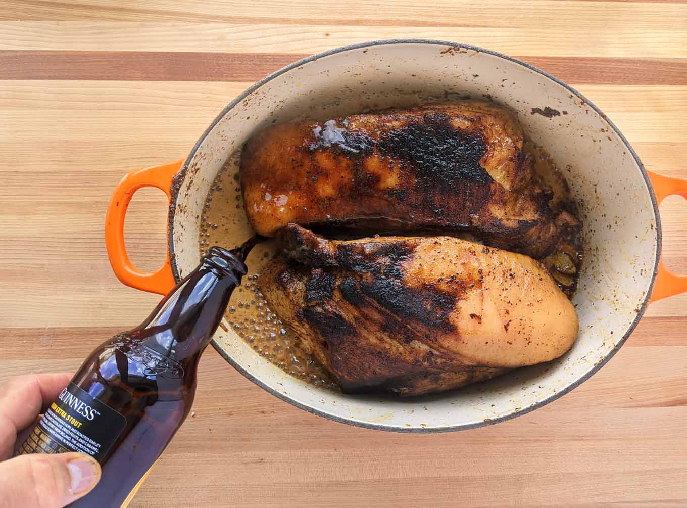 pouring a beer into the dutch oven with the seared pork roasts