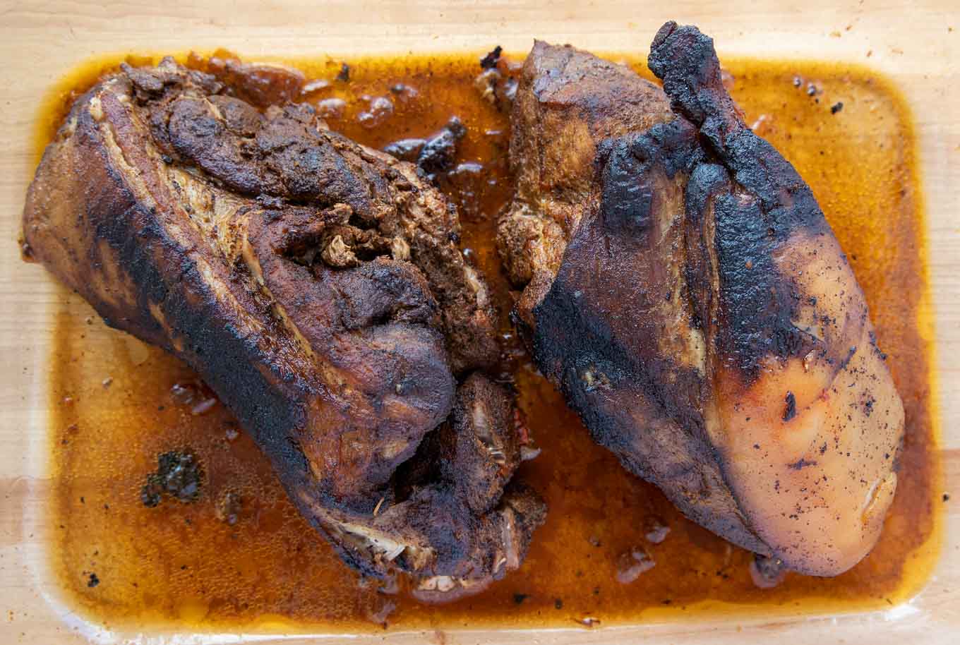  roasted pork butts in a glass baking dish with au jus in the dish for perfect pulled pork